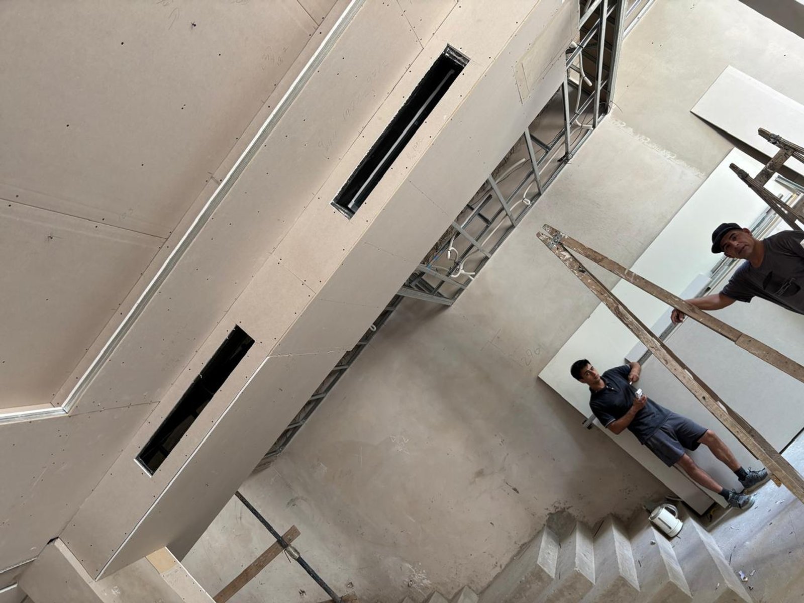 Interior em construção com escadas e trabalhadores — projeto INSTALACIONES, por CLIMA STAR SRL, em Pichincha 167